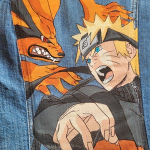 May include: A denim jacket featuring a vibrant, hand-painted design of an anime character with spiky blonde hair and blue eyes, facing an orange fox-like creature. The artwork is detailed with bold outlines and dynamic poses.