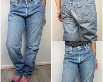 May include: Light blue denim jeans with a button fly and classic five-pocket design. The jeans have a faded wash and a relaxed fit. The back pocket features a red tag. The jeans are shown from multiple angles.