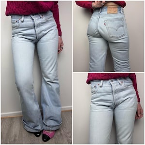 Puede incluir: Un par de pantalones vaqueros de mezclilla azul claro con pierna ancha y cintura alta. Los pantalones tienen un estilo clásico de cinco bolsillos y cierre de botón.