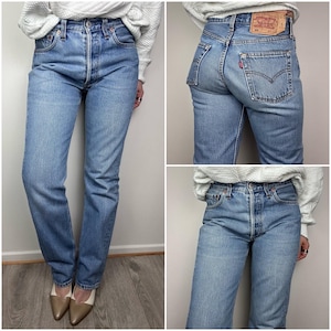 Könnte beinhalten: Hellblaue Jeans aus Denim mit Knopfleiste und klassischem Fünf-Taschen-Design. Die Jeans haben eine gerade Beinpassform und eine verwaschene Waschung. Ein rot-weißes Etikett ist auf der Gesäßtasche sichtbar.