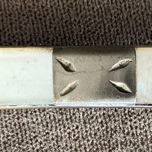 May include: A silver-toned metal handle featuring alternating rectangular inlays of iridescent white mother-of-pearl and polished metal sections. The metal segments are decorated with small, engraved leaf-like patterns.