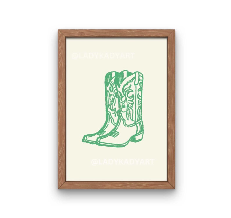 May include: A framed print featuring a green illustration of cowboy boots. The boots are detailed with decorative stitching and are set against a cream-colored background. The frame is made of wood.
