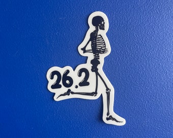 May include: A white sticker with a black skeleton running, with the number "26.2" in a speech bubble. The sticker is on a blue background. The skeleton is in a running pose, with its arms bent and legs extended.