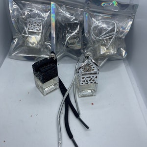 May include: Three silver and black car air fresheners with decorative metal cages and black and silver strings. The air fresheners are packaged in clear plastic bags.