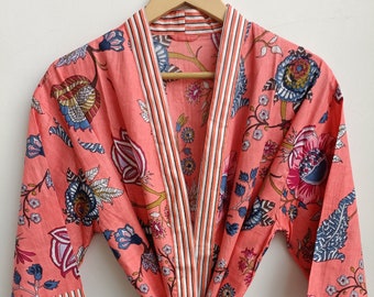May include: A coral pink floral print robe with a white and coral striped trim. The robe has a tie belt and three-quarter sleeves.