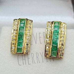 Puede incluir: Un par de pendientes de oro con detalles de esmeralda y diamantes. Los pendientes son de forma rectangular y presentan una fila de piedras de esmeralda rodeadas de piedras de diamante más pequeñas.