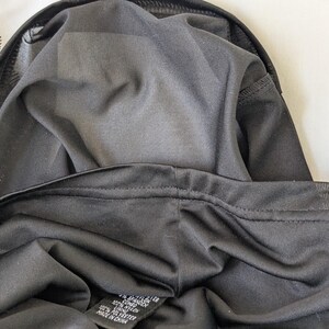 May include: Close-up of black lingerie, showcasing the fabric's texture and stitching details. The garment appears to be made of a soft, dark material, with a visible label indicating the fabric composition. The image highlights the inner lining and construction of the lingerie.