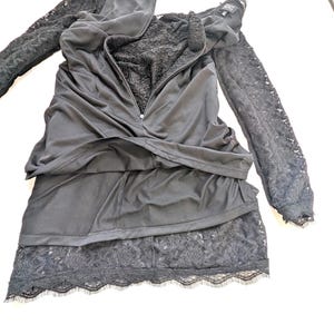 May include: Black dress with long lace sleeves and a tiered skirt. The dress features a zipper down the front and a lace trim at the hem. The bodice has a lace lining.