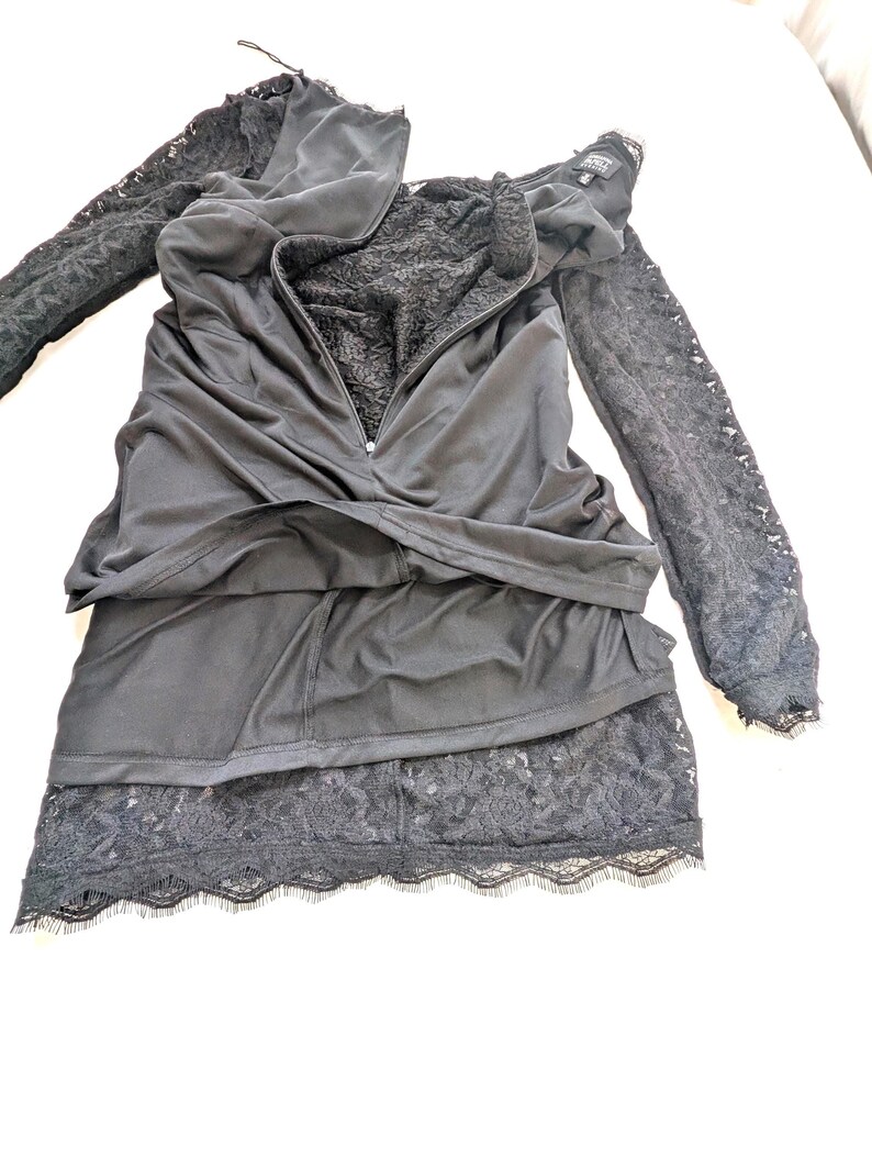 May include: Black dress with long lace sleeves and a tiered skirt. The dress features a zipper down the front and a lace trim at the hem. The bodice has a lace lining.