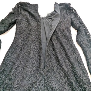 May include: A black lace dress with long sleeves and a high neckline. The dress features a floral pattern and a zipper down the back. The dress is made of a delicate lace fabric.