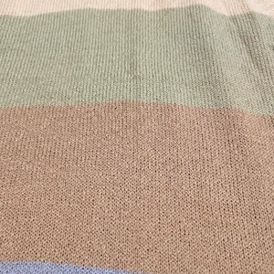 May include: Close-up of a knitted sweater with a V-neck collar. The sweater has horizontal stripes in cream, sage green, tan, and light blue. The knit fabric has a textured appearance.