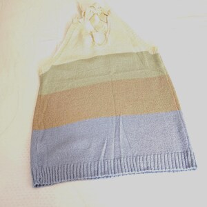 May include: A knitted top with a colour block design. The top features horizontal stripes in cream, olive green, tan, and light blue. The top has a halter neck design with cream-coloured ties.