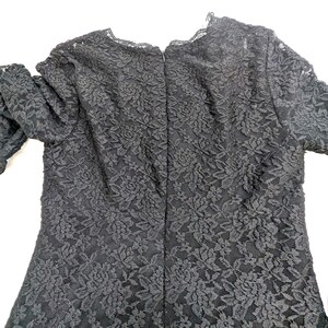 May include: Black lace dress with long sleeves. The dress features a floral pattern and a scalloped neckline. The back of the dress has a zipper closure.