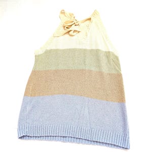 May include: A striped halter top with a cream-coloured bow at the neckline. The top has horizontal stripes in cream, green, tan, and light blue. The bottom hem is a ribbed knit. The garment is sleeveless.