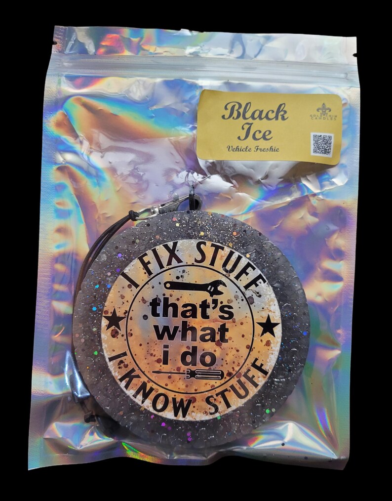 K&ouml;nnte beinhalten: Ein runder, schwarzer Lufterfrischer mit Glitzer und dem Text "I FIX STUFF, that's what I do, I KNOW STUFF." Der Lufterfrischer befindet sich in einer transparenten, irisierenden Verpackung mit einem "Black Ice"-Etikett.