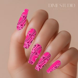 May include: Pink and black bandana print nail wraps. The nail wraps are long and have a paisley design.