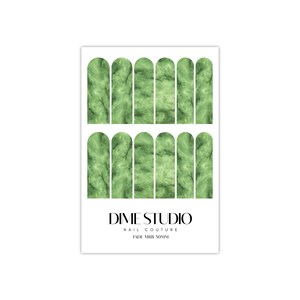 May include: Green marble nail wraps with a rounded shape. The nail wraps are arranged in two rows of six. The text "DIME STUDIO NAIL COUTURE JADE MIRB 50MM" is printed below the nail wraps.