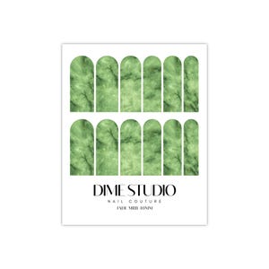May include: Green marble nail wraps with a white outline. The nail wraps are arranged in two rows of seven. The text "DIME STUDIO NAIL COUTURE JADE MARB 10MM" is printed below the nail wraps.
