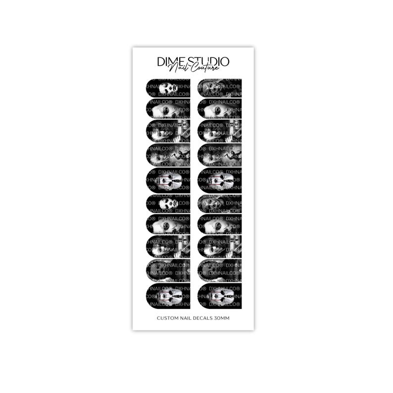 Pode incluir: Uma folha de decalques para unhas em preto e branco da DIME STUDIO Nail Couture com v&aacute;rias imagens de caveiras e esqueletos. A folha retangular cont&eacute;m vinte adesivos individuais em formato de unha com o texto CUSTOM NAIL DECALS 30MM na base.
