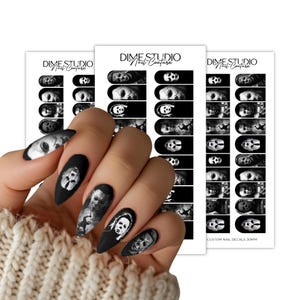 Pode incluir: Um conjunto de decalques de unhas em preto e branco com imagens de personagens de filmes de terror da Dime Studio Nail Couture. Os decalques s&atilde;o apresentados em tr&ecirc;s folhas retangulares, cada uma contendo v&aacute;rios designs de arte.