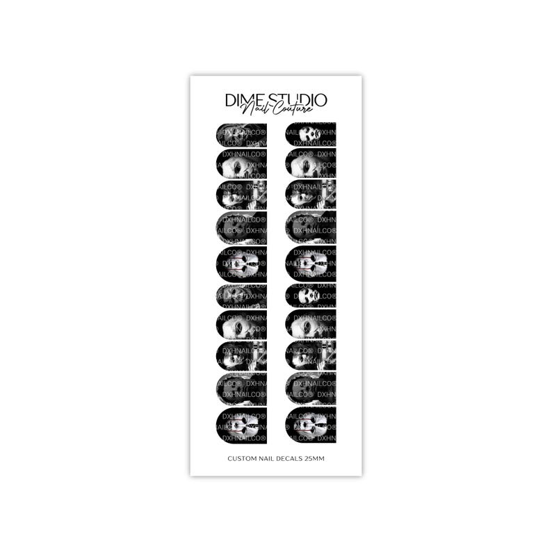 Pode incluir: Uma folha retangular de decalques de unhas em preto e branco com desenhos de caveiras. O texto superior diz DIME STUDIO Nail Couture e o texto inferior diz CUSTOM NAIL DECALS 25MM. A folha cont&eacute;m vinte adesivos em formato de unha.