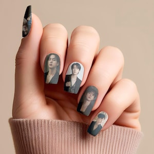 May include: Nail art featuring images of a male musical artist. The nail designs showcase various portraits of the artist on a neutral background. The nails are painted with a glossy finish, creating a stylish and eye-catching look. The nail art is a unique form of self-expression.