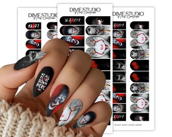 Pode incluir: Um conjunto de decalques para unhas com imagens do palhaço Pennywise, incluindo balões vermelhos, o texto "WE ALL FLOAT DOWN HERE" e "LOVER" com um "A" vermelho. Os designs estão impressos em folhas brancas com o rótulo "DIME STUDIO Nail Couture."