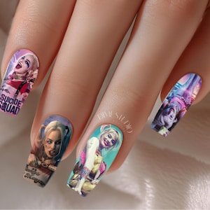 Pode incluir: Close-up de unhas com arte de unhas colorida com imagens de Harley Quinn do filme Esquadrão Suicida. A arte de unhas inclui as palavras "Suicide Squad" e "Daddy's Little Monster".