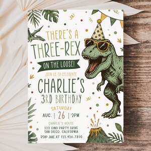 Pu&ograve; includere: Un biglietto d'invito per compleanno con un T-Rex verde che indossa un cappellino da festa e occhiali da sole. Il testo recita: THERE'S A THREE-REX ON THE LOOSE! JOIN US TO CELEBRATE CHARLIE'S 3RD BIRTHDAY, SATURDAY AUG. 26 2PM, CHARLIE'S HOUSE 123 DINO PARTY DRIVE.