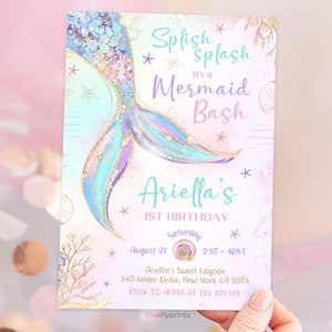 K&ouml;nnte beinhalten: Eine Einladung zu einer ersten Geburtstagsfeier zum Thema Meerjungfrau mit einem glitzernden t&uuml;rkisfarbenen und violetten Meerjungfrauen-Schwanz, einem rosa und wei&szlig;en Hintergrund und dem Text "Splish Splash It's a Mermaid Bash Ariella's 1st Birthday August 21 Saturday 2:30-4PM Ariella's Sweet Lagoon 340 Under Drive, New York CA 9903 RSVP TO ANNA AT 123 321 123"