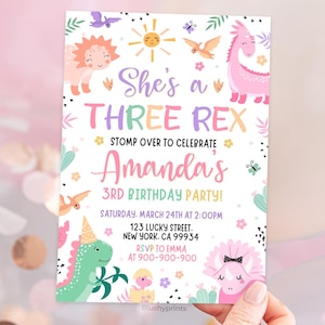 K&ouml;nnte beinhalten: Eine rosafarbene und gr&uuml;ne Dinosaurier-Geburtstagseinladung mit dem Text "She's a Three Rex" und "Amanda's 3rd Birthday Party!" Die Einladung enth&auml;lt ein Datum, eine Uhrzeit und einen Ort f&uuml;r die Party.