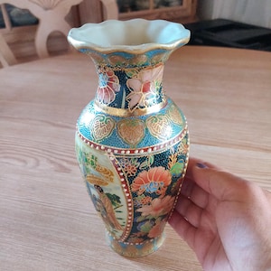 Könnte beinhalten: Eine kleine, blaue und goldene Keramikvase mit weißem Rand und aufwendigen floralen und geometrischen Mustern. Die Vase zeigt eine Szene mit Menschen in traditioneller japanischer Kleidung.