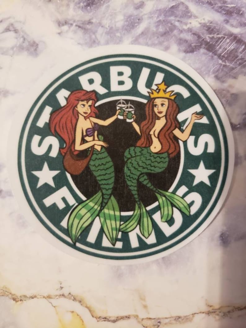 May include: A green and white Starbucks logo with the word "FRIENDS" written around the outside. Two mermaids, one with red hair and one with brown hair, are holding Starbucks cups and smiling.