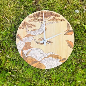 Könnte beinhalten: Eine Holzuhr mit einem eingebrannten Holzdesign eines Baumes mit weißen Linien. Die Uhr hat weiße Zeiger und ist vor einem Hintergrund aus grünem Moos platziert.