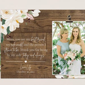 May include: A rustic wood background with a white floral design and a photo of a bride and her mother. The text reads "Mom, you are my best friend, my role model, and the person I strive to be. Thank you for being by my side today and always. Love Lily October 30, 2021."