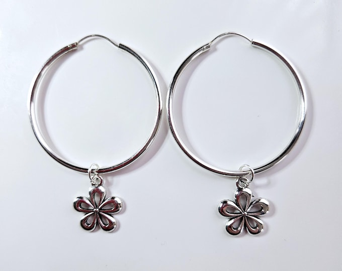 Sterling silver endless hoop earring with silver flower charm dangle.