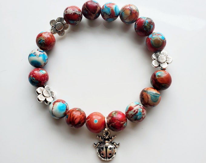 Red and light blue imperial jasper gemstone bracelet with silver ladybug charm.