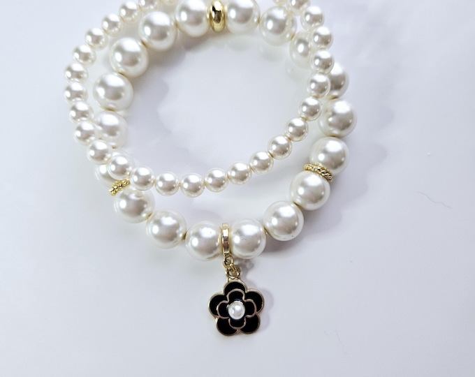 White Austrian crystal flower power pearl bracelet duo with black enamel and gold plated flower charm.