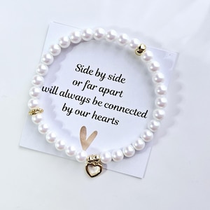 Connected by our heart&#39;s 2 armbandenset gemaakt met parelmoerwitte parels en een met goud gevulde hartbedel.