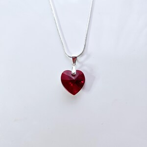 May include: A silver chain necklace with a red heart-shaped pendant.