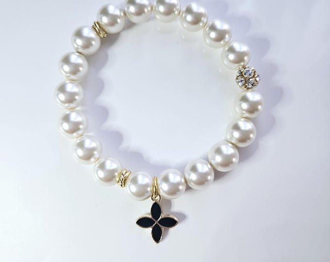 Austrian crystal pearlescent white pearl beads and white enamel and gold iconic flower charm.