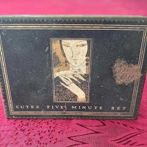 May include: A vintage Cutex Five Minute Set box. The rectangular box has a black background with gold trim. The front features an art deco illustration of a woman with long earrings. The text "CUTEX FIVE MINUTE SET" is printed on the bottom.