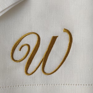 May include: White linen napkin with a gold embroidered letter W.
