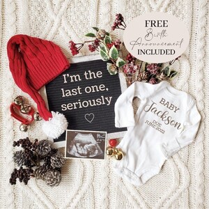 May include: A white onesie with the text "BABY Jackson DUE JUNE 2022" in brown script. A red Santa hat with a white pom-pom, a black letter board with the text "I'm the last one, seriously", and a sonogram photo are also in the image.