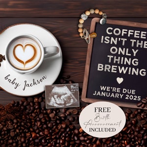 Pode incluir: Um letreiro de quadro-negro com o texto "Café não é a única coisa que está a ser preparada. Estamos à espera em janeiro de 2025." Uma chávena de café com um desenho de coração na espuma está sobre um pires com o texto "bebé Jackson". Uma pequena imagem de ultrassom e grãos de café estão espalhados à volta do letreiro e da chávena.