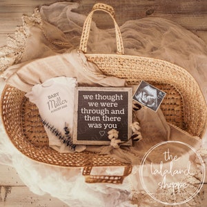 Peut inclure: Un panier en osier rempli d'une grenouillère blanche qui dit "BABY Miller AUGUST 2022", un tableau à lettres avec le texte "we thought we were through and then there was you", et une image d'échographie en noir et blanc.