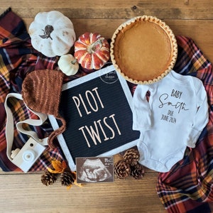 Op de afbeelding: Een baby-aankondiging in herfstthema met een letterbord waarop "PLOT TWIST" staat, een wit rompertje met de tekst "BABY Smith DUE JUNE 2024", een pompoen, een taart en een echo-foto.