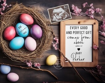 May include: A wooden frame with a white background and black text that reads "Every good and perfect gift comes from above James 1:17" with a black heart and the text "Baby Parker". The frame is sitting on a wooden surface with a nest of colourful eggs and a black and white ultrasound image.