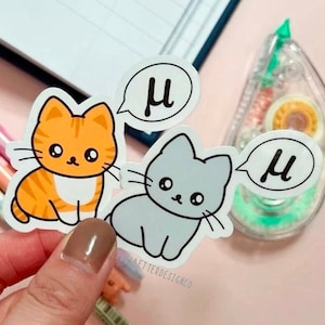 Peut inclure: Deux autocollants de chat de dessin animé avec des bulles de dialogue. Le chat orange a une poitrine blanche et le chat gris a un ventre blanc. Les deux bulles de dialogue contiennent la lettre grecque mu.