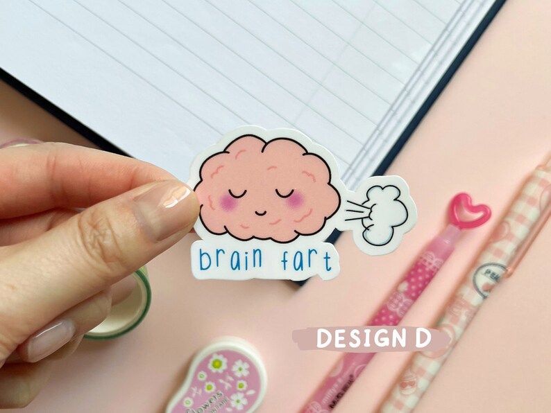 May include: A pink brain cartoon sticker with a cloud of smoke coming out of its mouth. The sticker says "brain fart" in blue text.